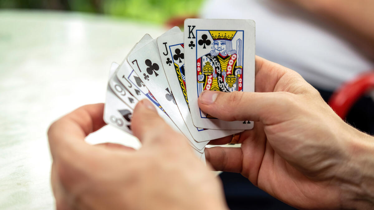 man-playing-cards-with-other-people-holding-deck.jpg