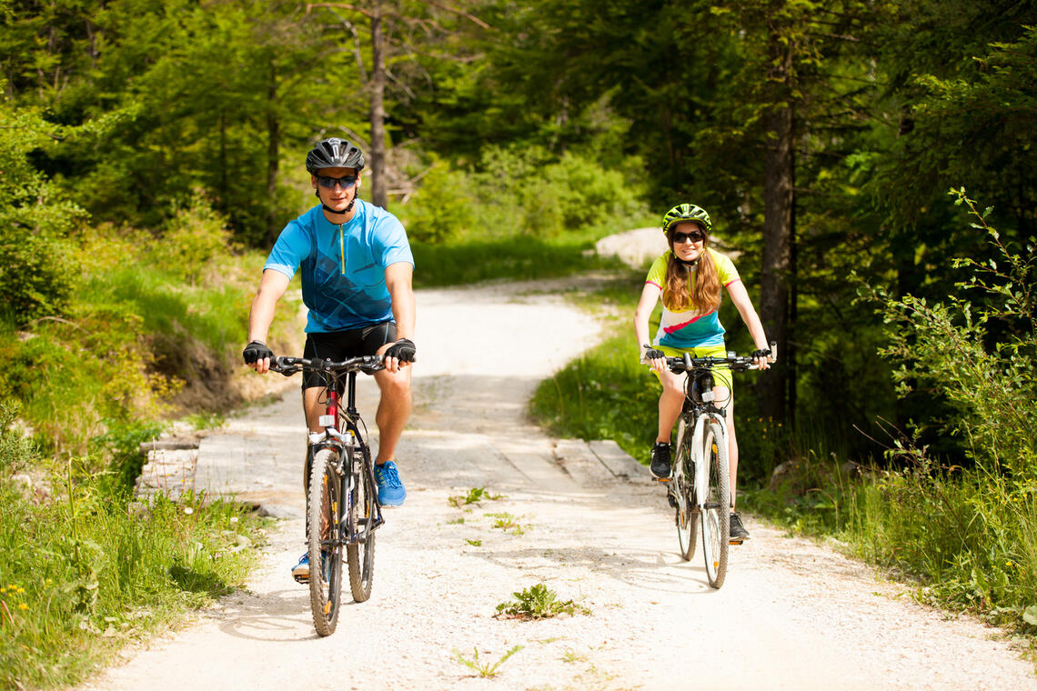 ACTIVE Young couple biking on a forest road in mountain on a spring day