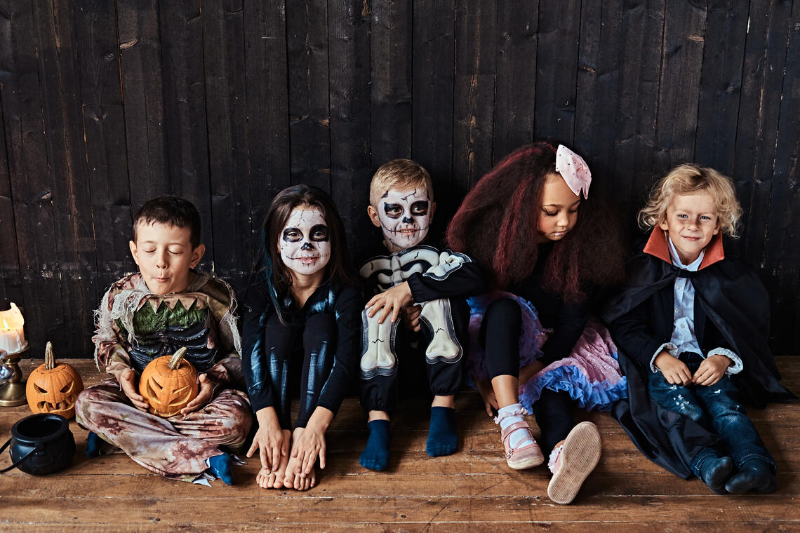 Halloween party with group children who sitting together on a wooden floor in an old house