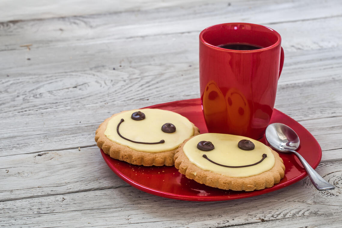 smile cookies on a red plate with Cup of coffee, wooden background, food