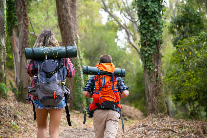 Back view of backpackers walking on mountainous trail