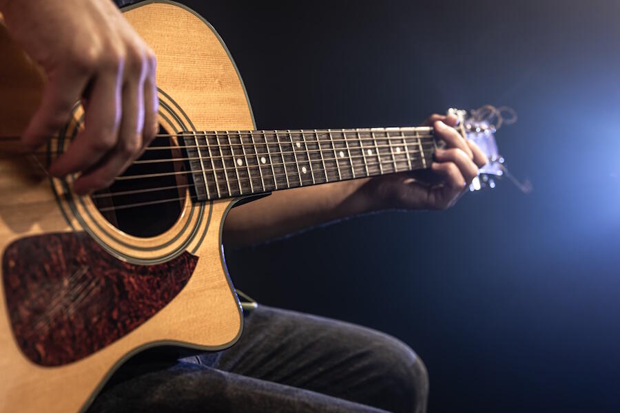 Close-up shot of guitarist playing acoustic guitar, copy space.