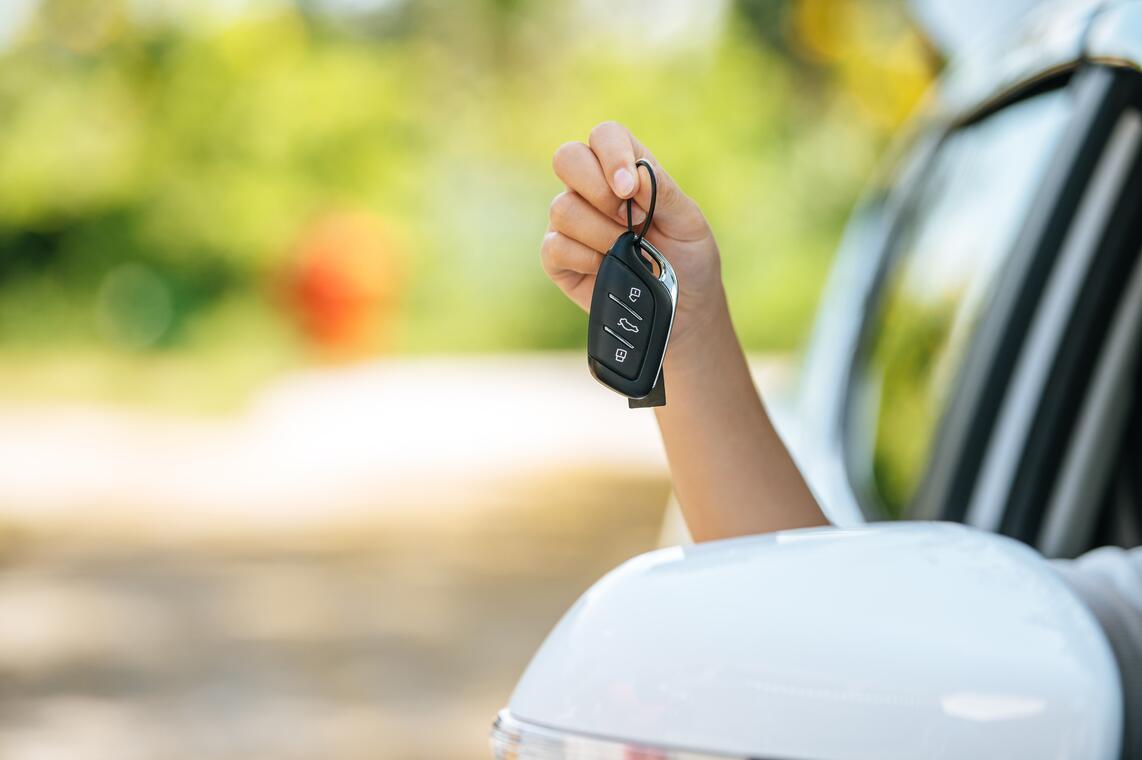 AUTOMOBILE girl-sitting-car-holding-car-keys-hands-out-car-min