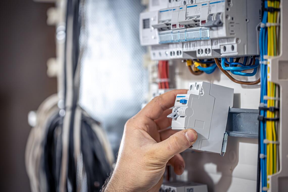 ELECTRICIEN - male-electrician-works-switchboard-with-electrical-connecting-cable-min