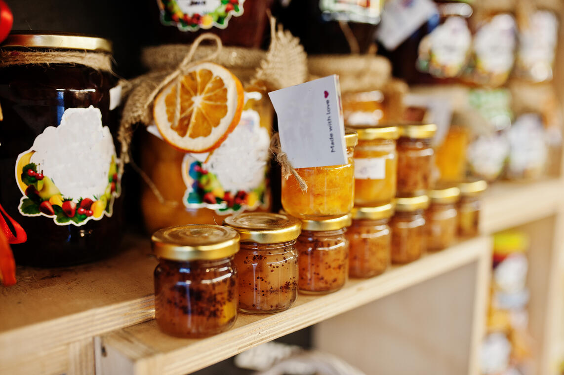 Glass jars with different kinds of jam and berries of a supermarket shelves or grocery store. Homemade canning products. Made with love.