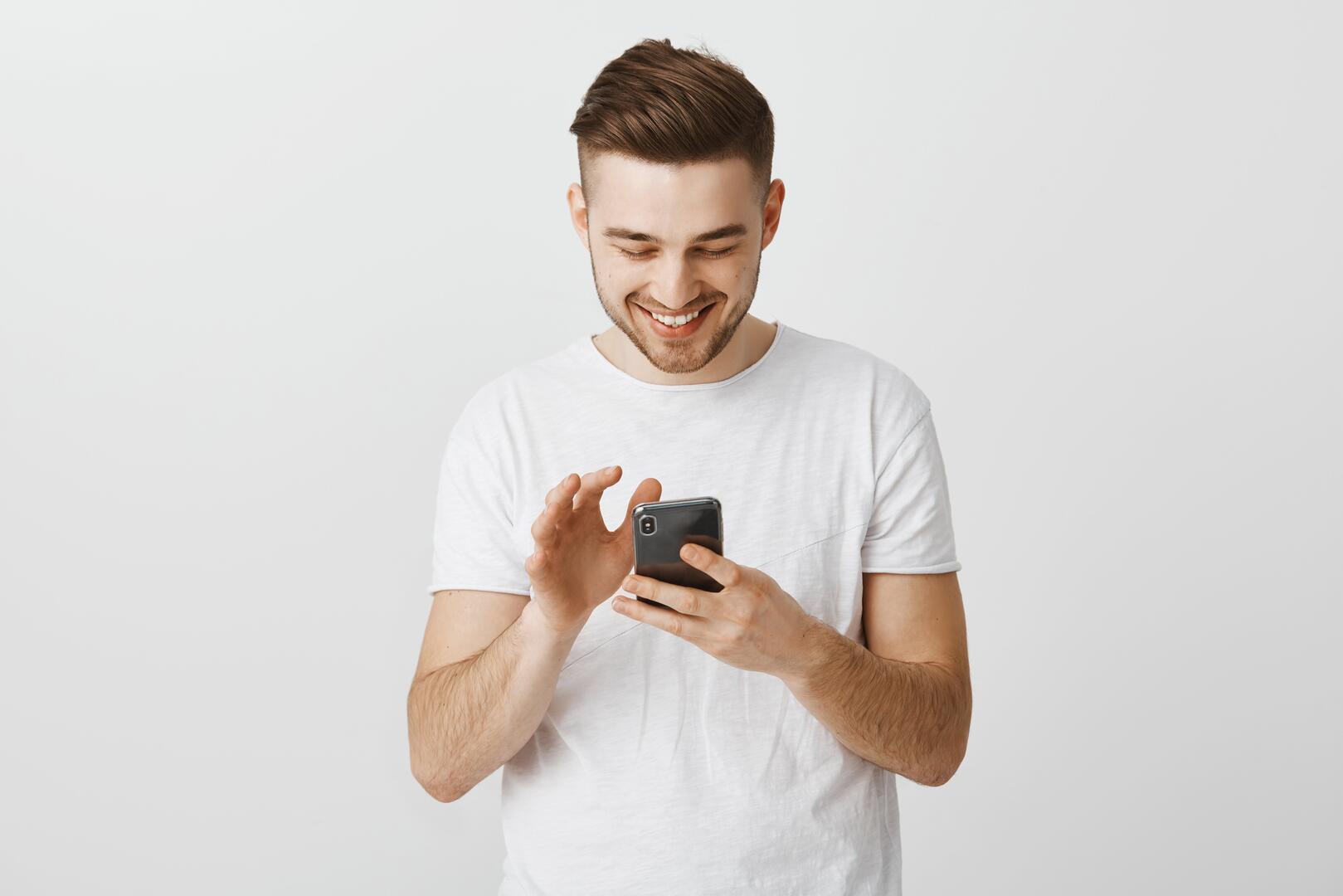 smiling-happy-young-man-using-mobile-phone-messaging-with-smartphone
