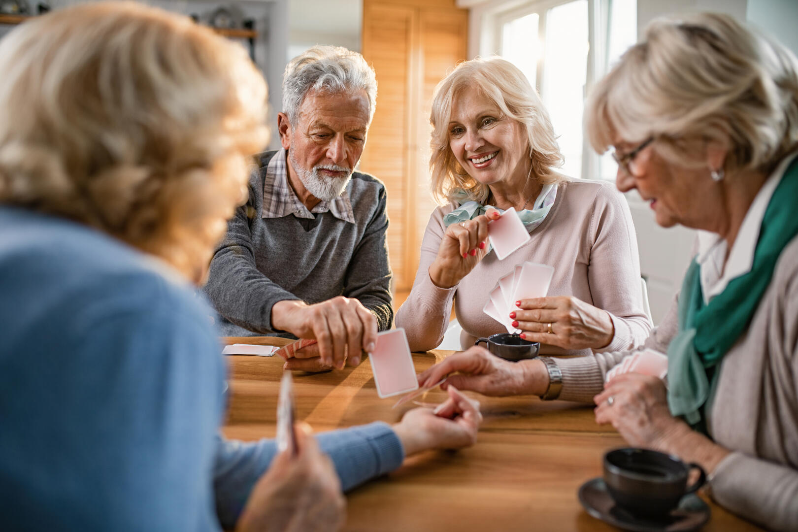 Small group of mature friends enjoying while playing cards at home.