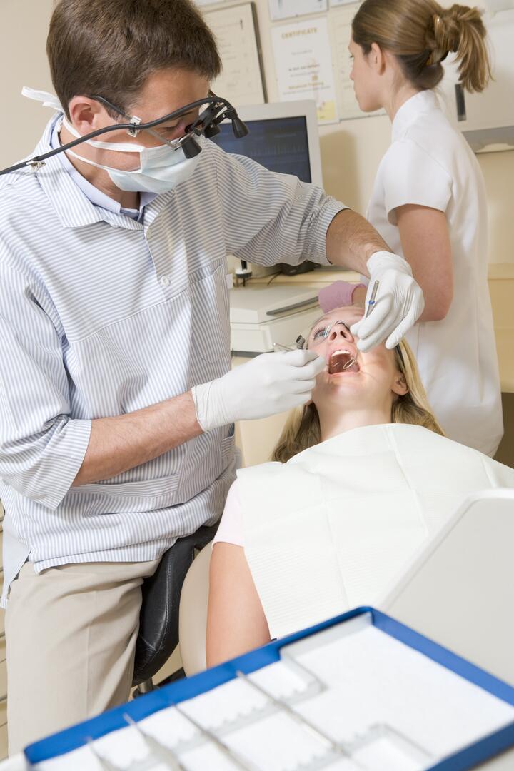 Dentist and assistant in exam room with woman in chair