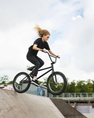 BMX rider is jumping over ramp outdoors