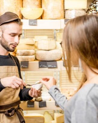 Salesman with a woman customer choosing a cheese for buying at the food store