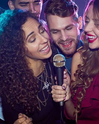 Group of cheerful young people singing together in karaoke