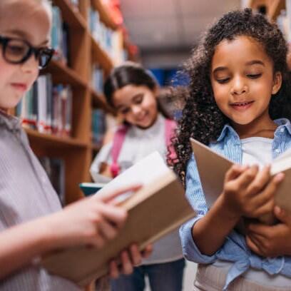 beautiful little schoolgirls looking for books in library