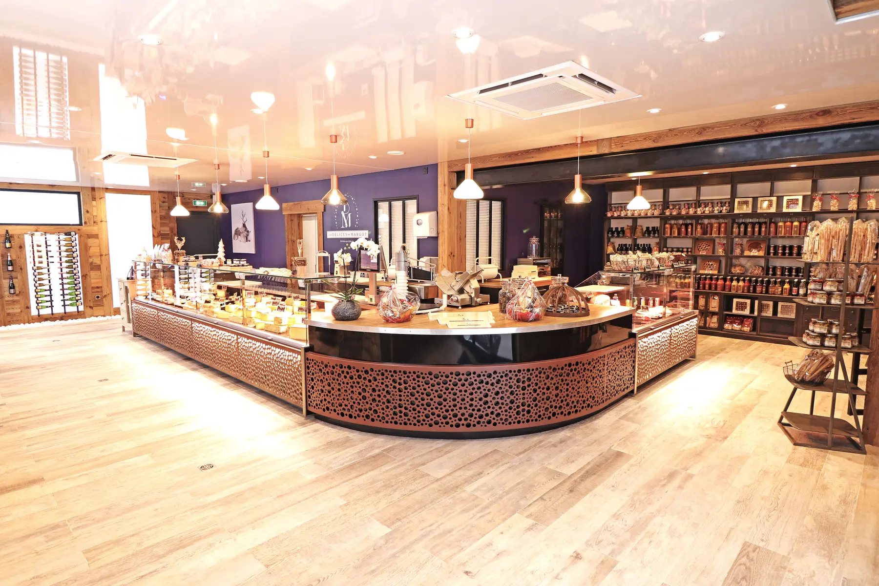 Entrée du magasin des Délices de Margot, avec un comptoir arrondi au premier plan et des étagères avec des produits dans le fond.