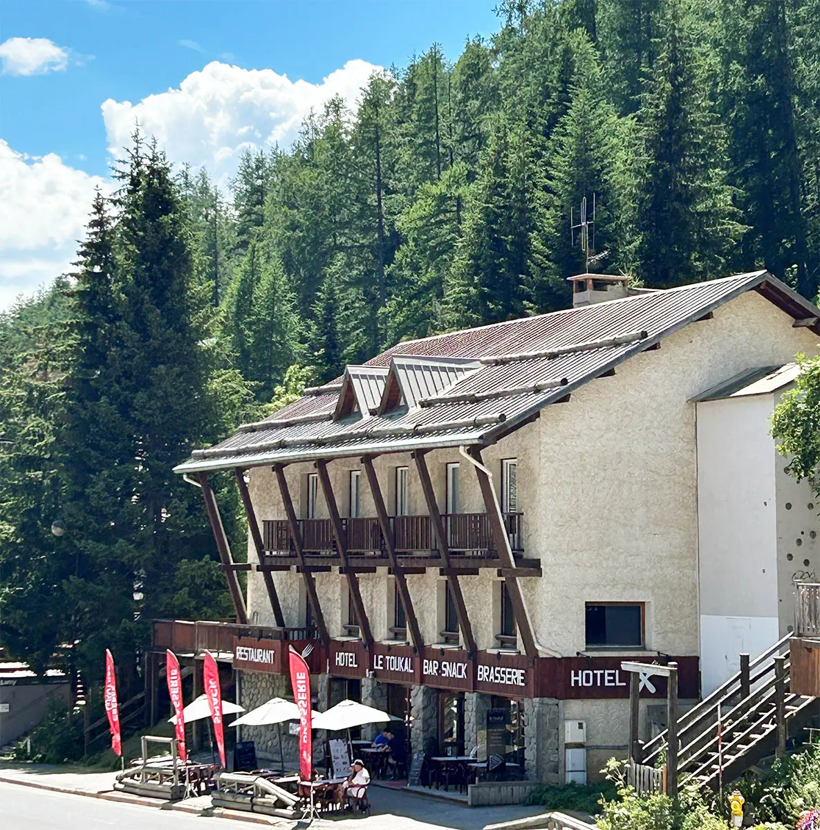 Vue de la brasserie sur 3 étages, bâtiment en pierre et bois avec terrasse en rdc et balcons