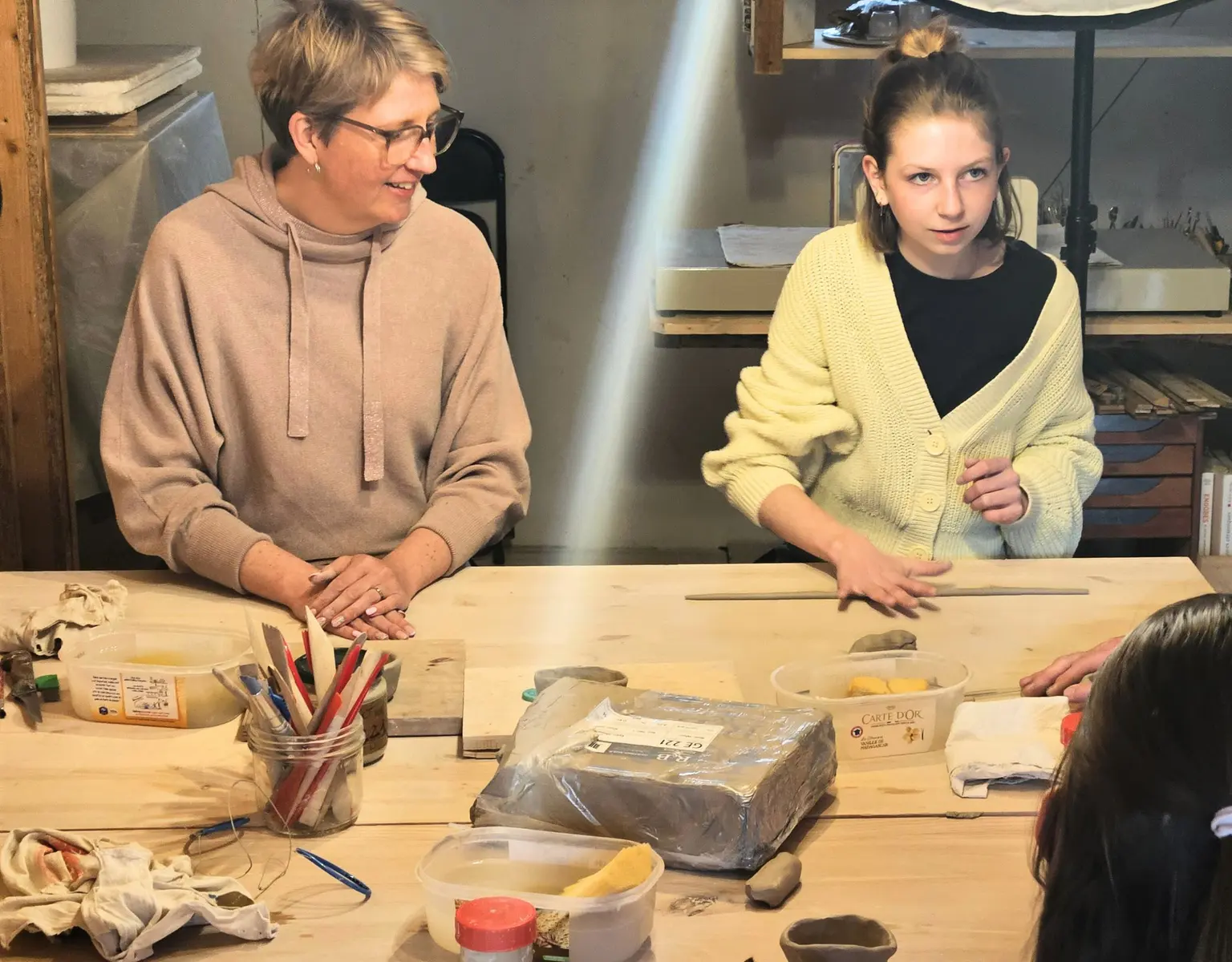 une femme et une jeune fille en atelier de poterie