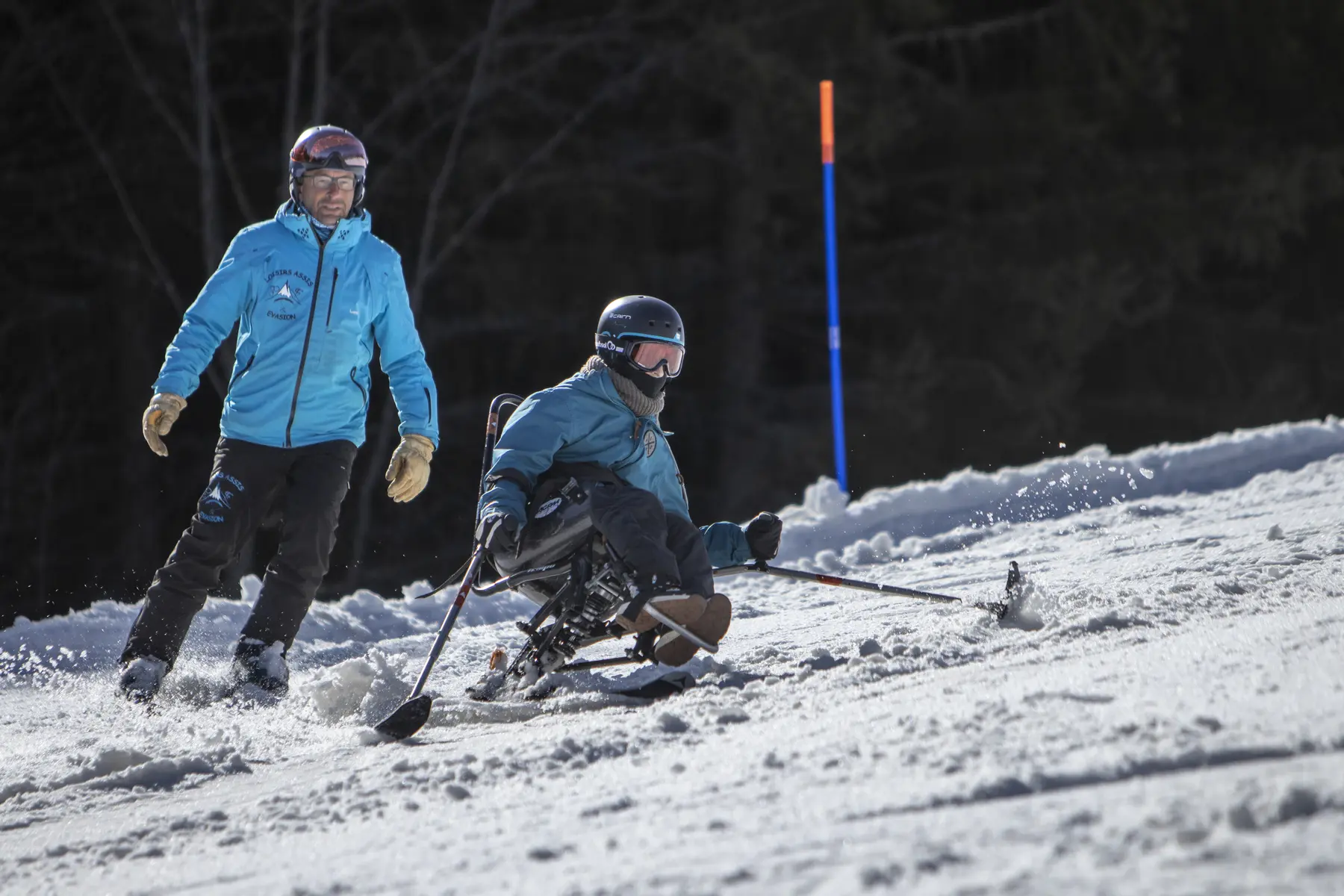 Un moniteur de ski donnant un cours d'uniski à une personne