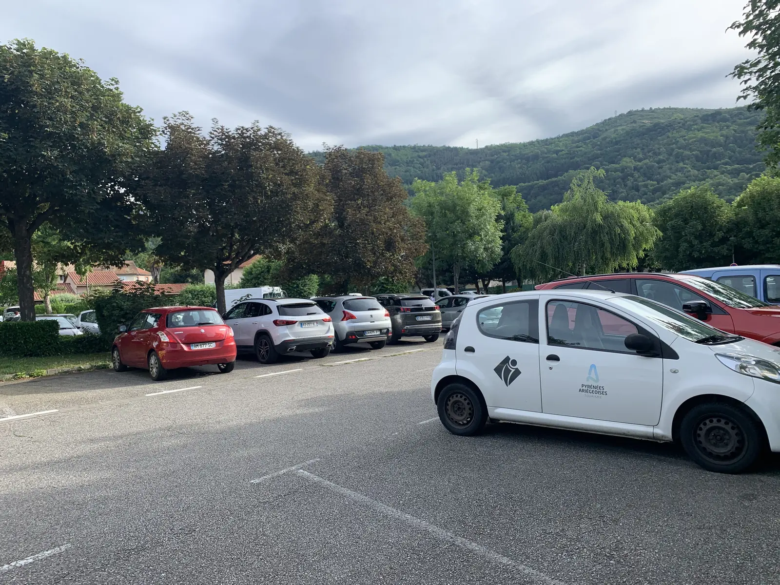 Le parking par une journée lumineuse mais nuageuse avec la voiture de l'office de tourisme en premier plan