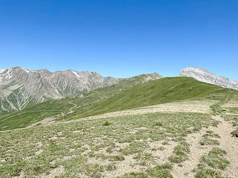 Vue de l'itinéraire de VTT AE au sommet du col d'Allos, sentier d'altitude sur une prairie d'altitude avec montagnes en arrière-plan