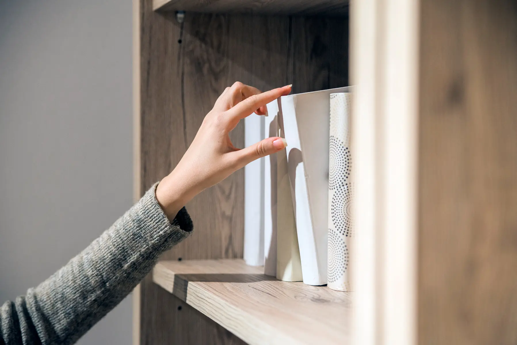Une main de femme se saisi d'un livre dans un bibliothèque