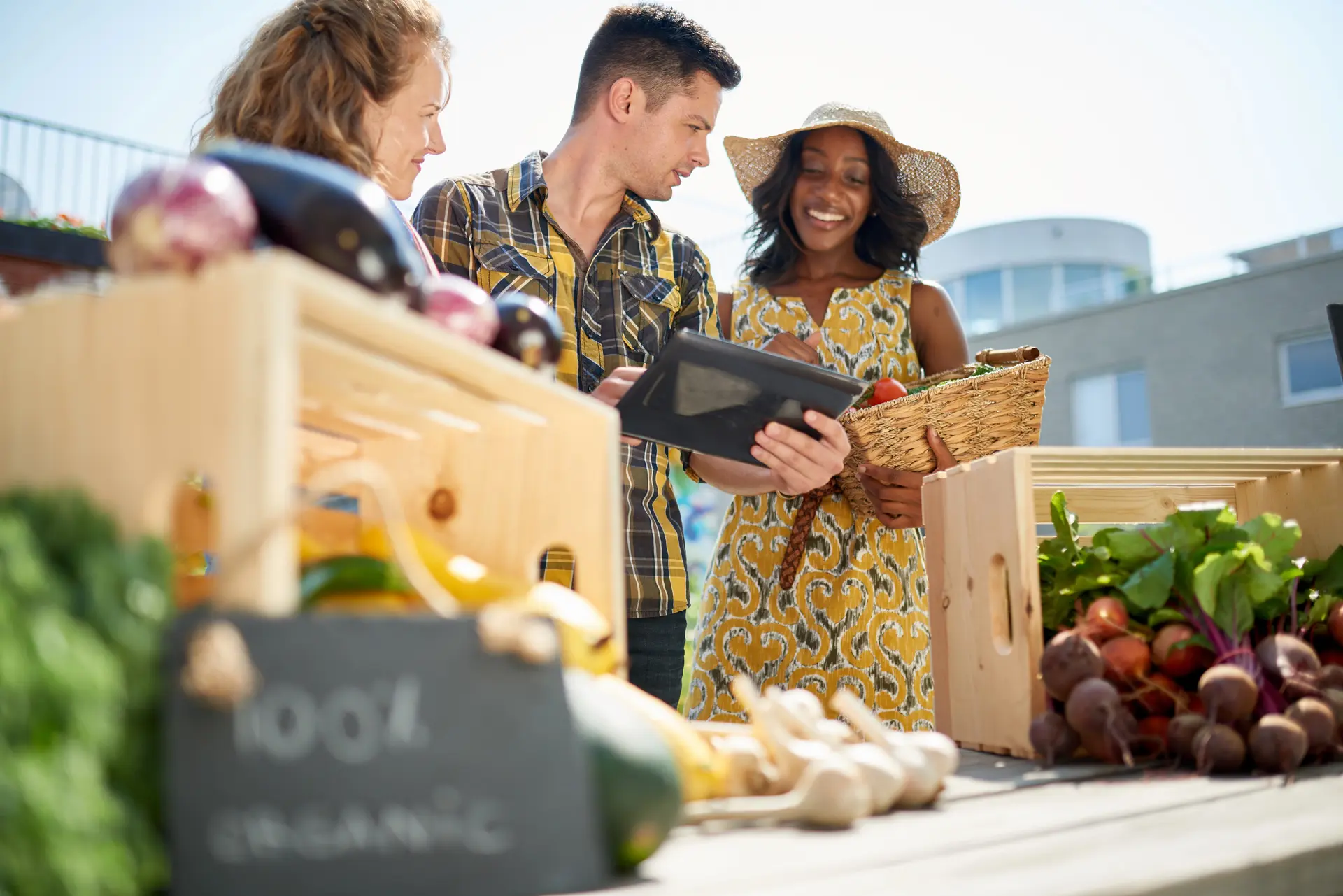 Friendly woman tending an organic vegetable stall at a farmer's market and selling fresh vegetables from the rooftop garden