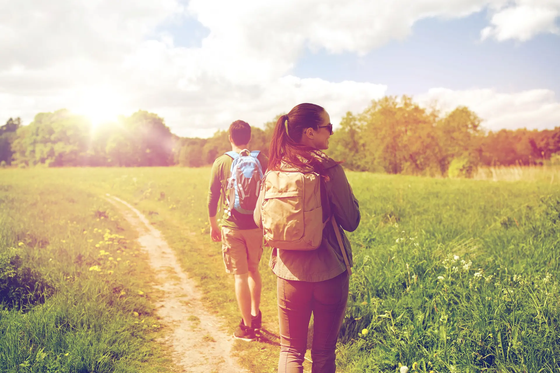 happy couple with backpacks hiking outdoors