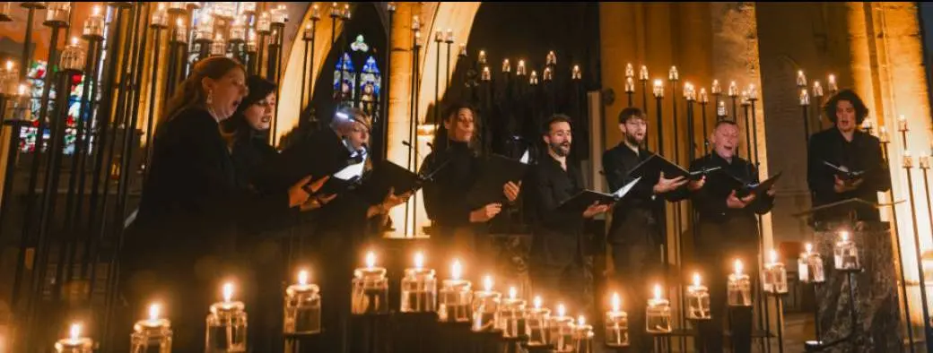 chorale qui chante dans une nef éclairée par des bougies