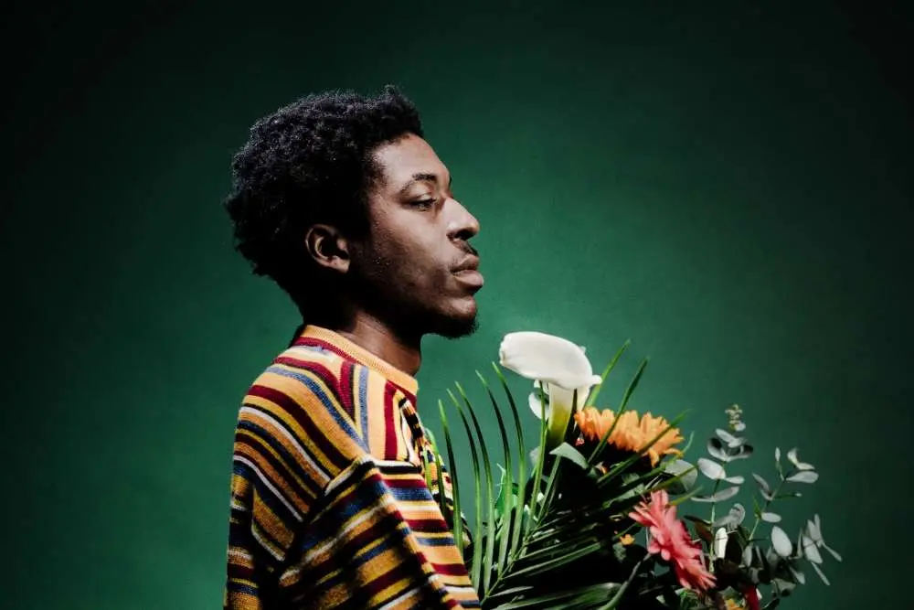 l'artiste de face avec un pull rayé et un bouquet de fleurs