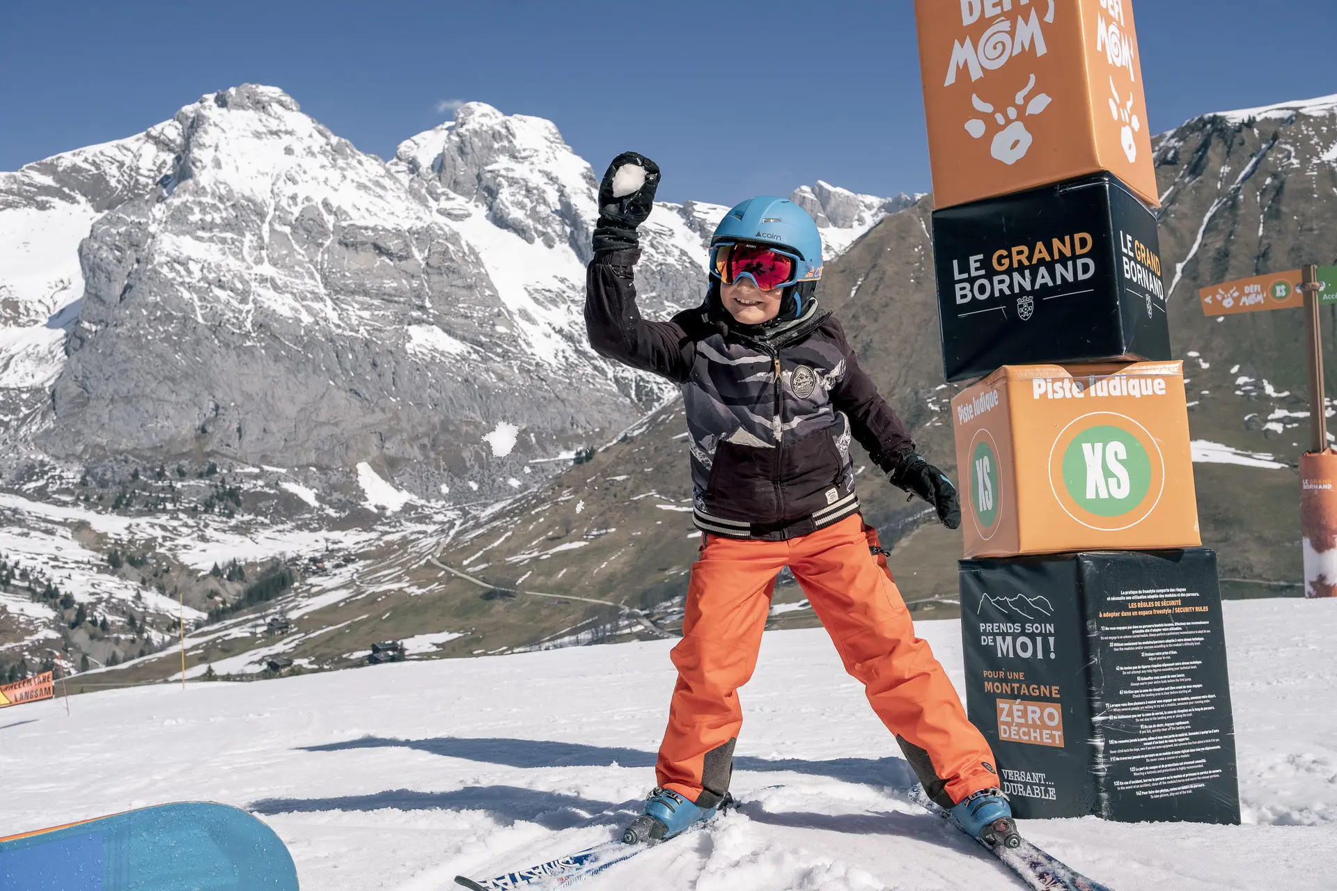 enfant à ski qui lance une boule de neige