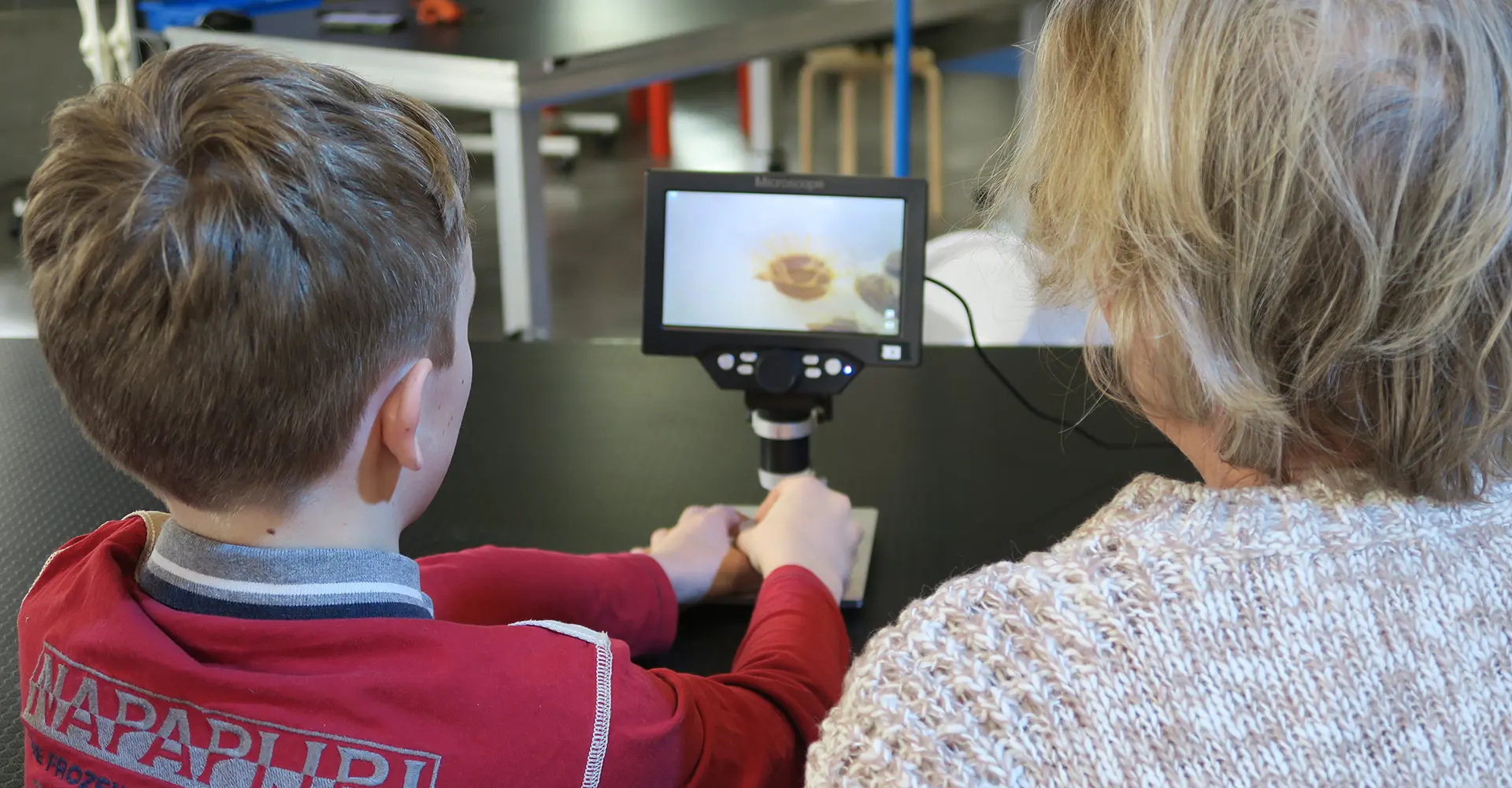 Un enfant et sa grand-mère devant un microscope