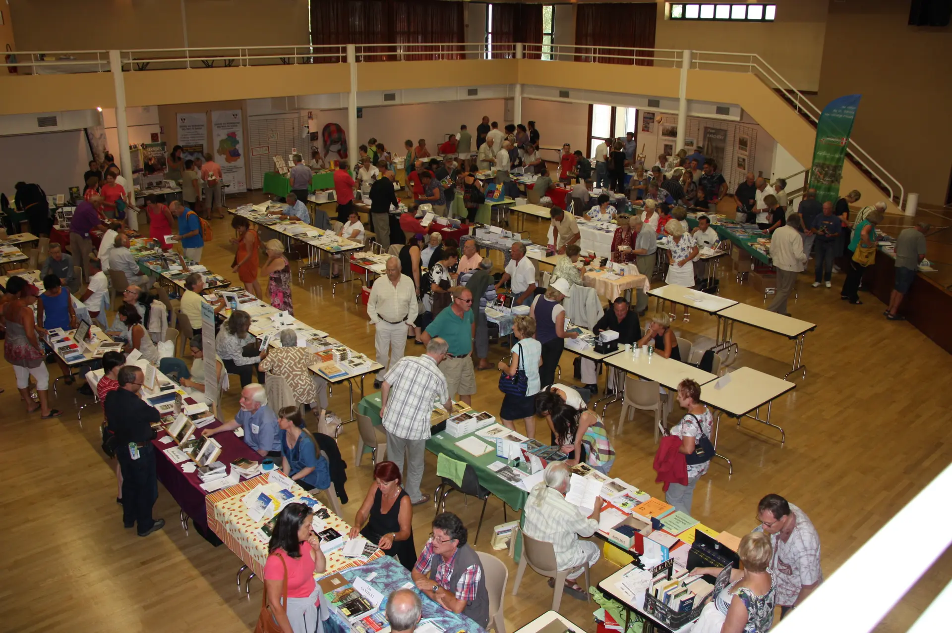 hall d'une salle avec des stand d'auteurs et des gens qui observent