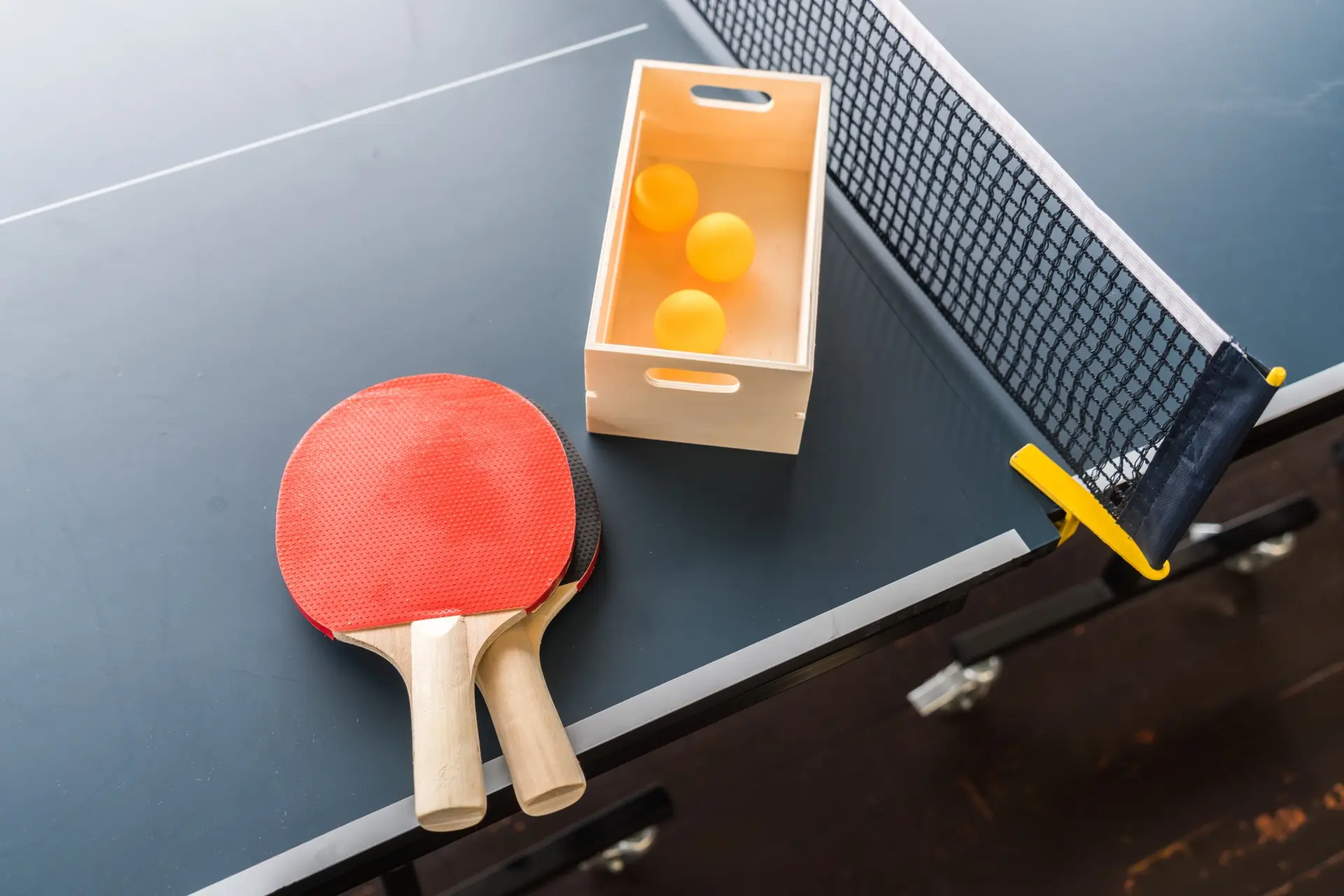 Deux raquette de tennis de table et des balles posées sur une table