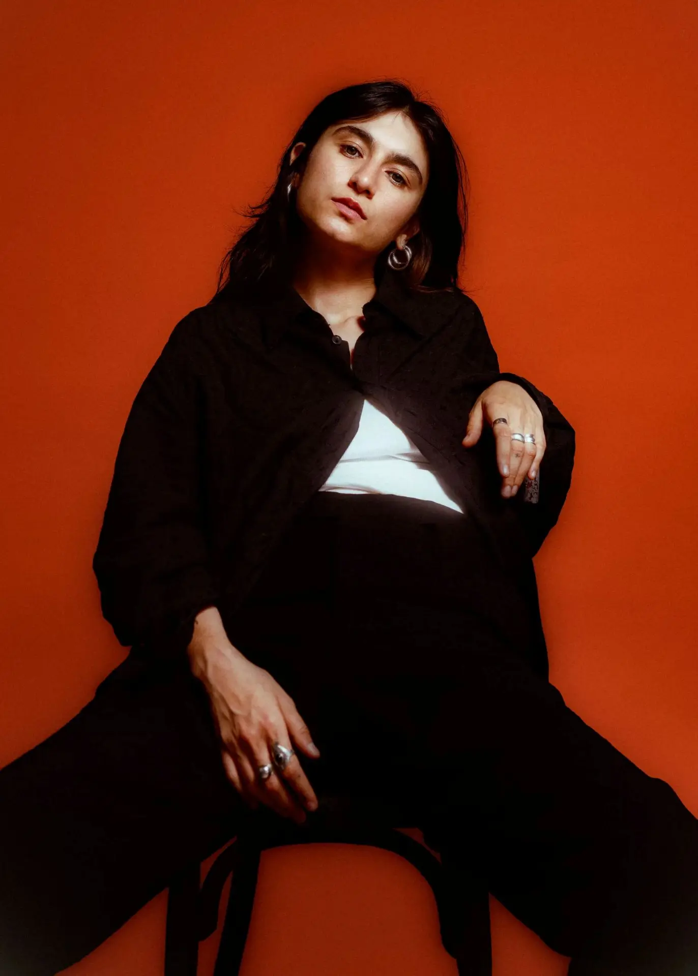 ariste ma assise sur une chaise sur fond rouge