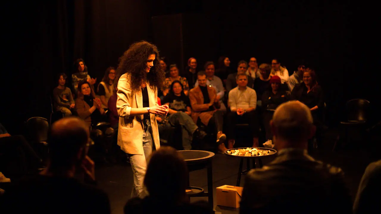 Artiste sur schène, tailleur pantalon blanc et le public autour d'elle