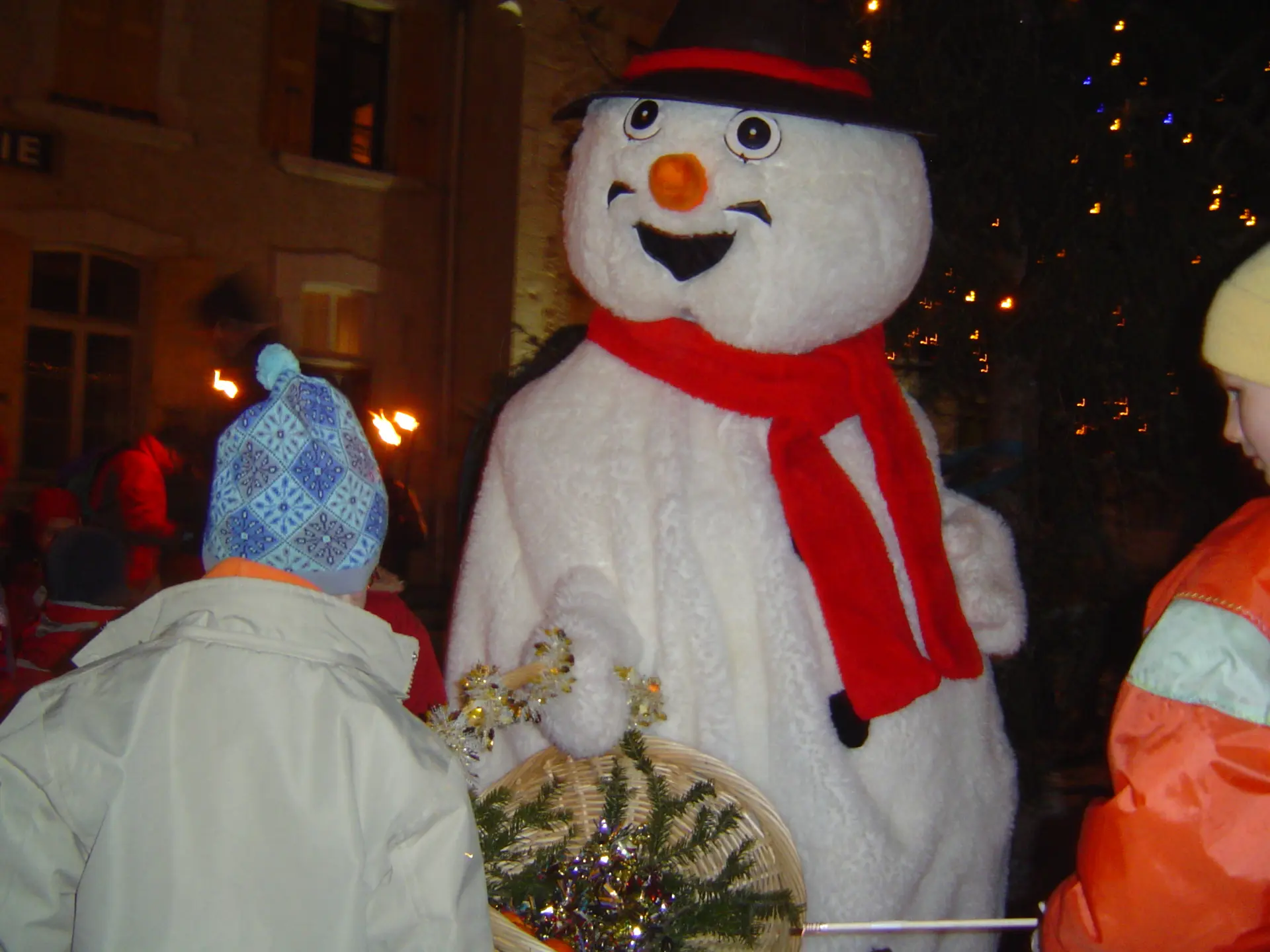 Mascotte de Caly le bonhomme de neige, tenant un panier dans les mains