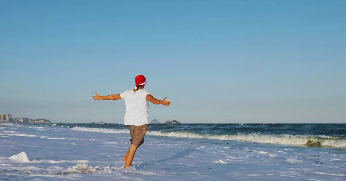 homme avec bonnet de Père Noël se baigne dans la mer