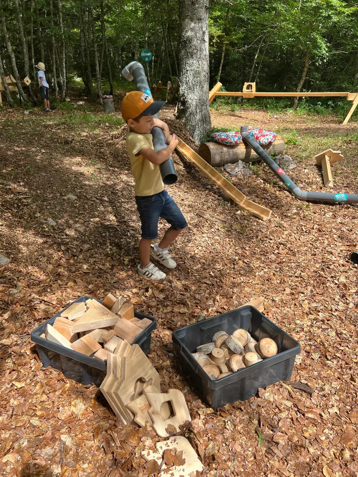 Enfant portant un tube de PVC pour créer son parcours Roule ma Boule dans la forêt