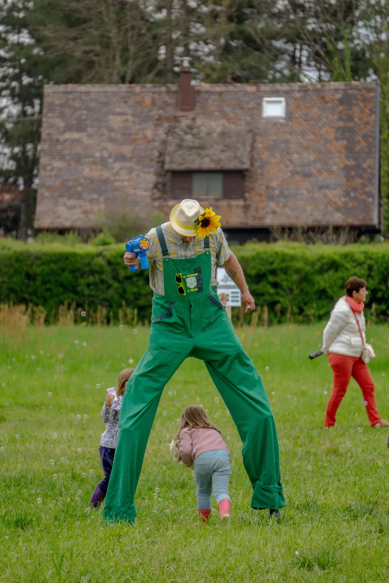 Des enfants jouent avec un homme sur des échasses