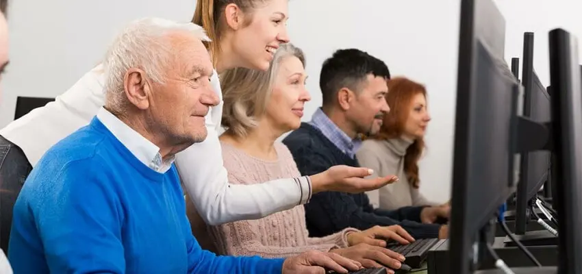 Photo d'un groupe de personnes devant des ordinateurs et en train de partager des connaissances