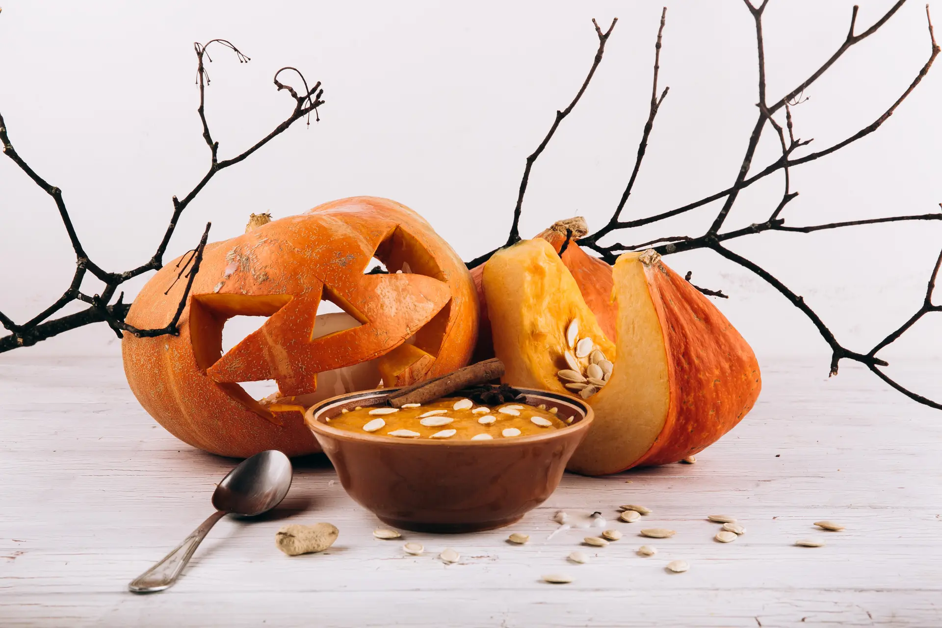 Une soupe de potimarron avec une citrouille d'Halloween derrière.