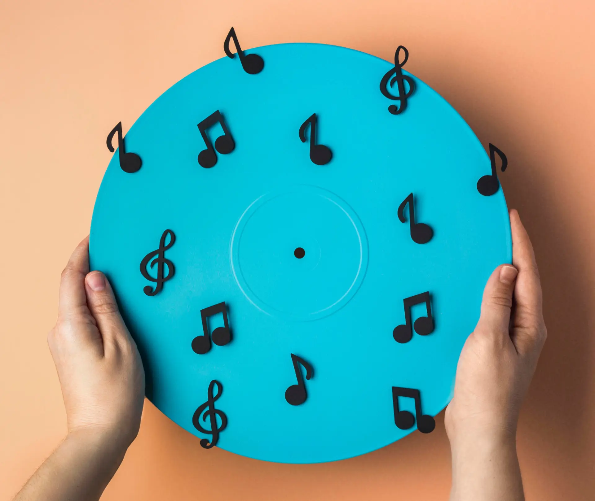 Des symboles musicaux sur un disque bleu, tenu par des mains