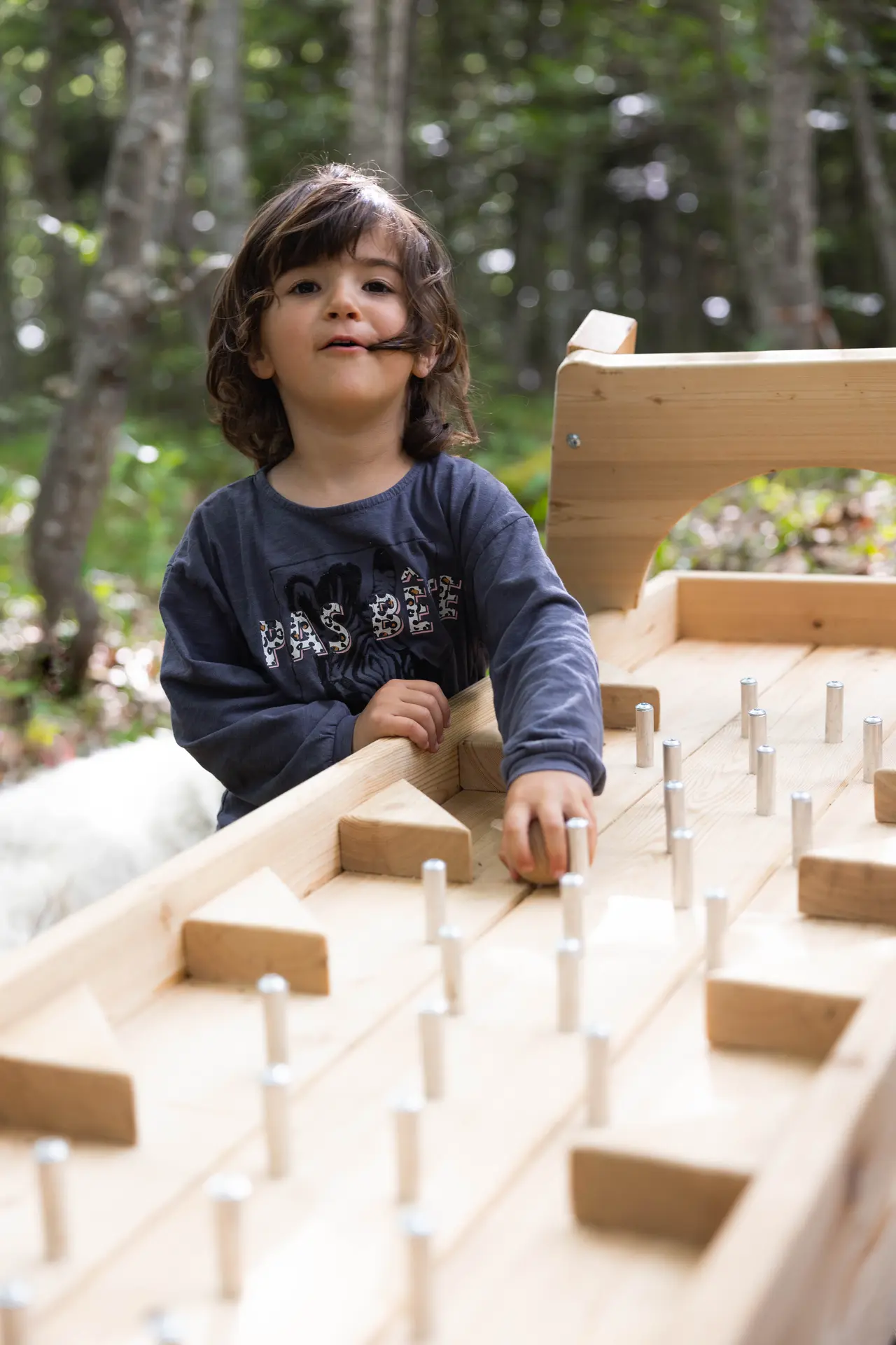Enfant tenant sa boule avant le la lâcher dans l'un des obstacles en bois avec des piques, sur le parcours permanent de Roule ma Boule, dans la forêt
