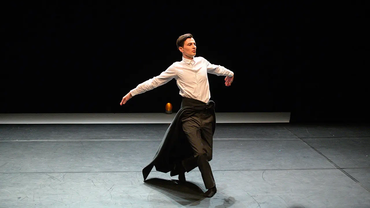 danseur homme seul sur scène qui fait un mouvement ample des bras