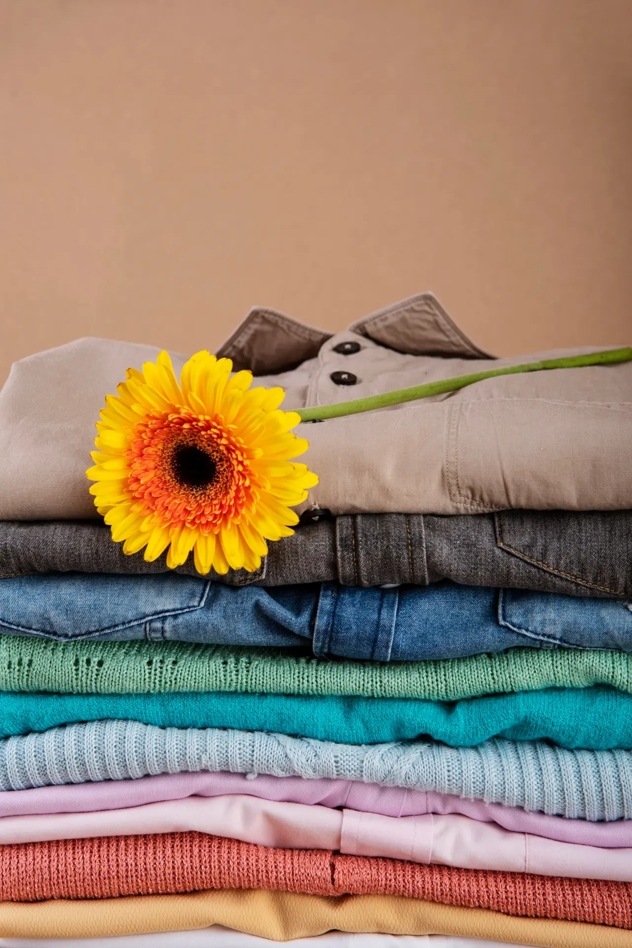 Une pile de vêtements d'enfants avec une fleur posée dessus.