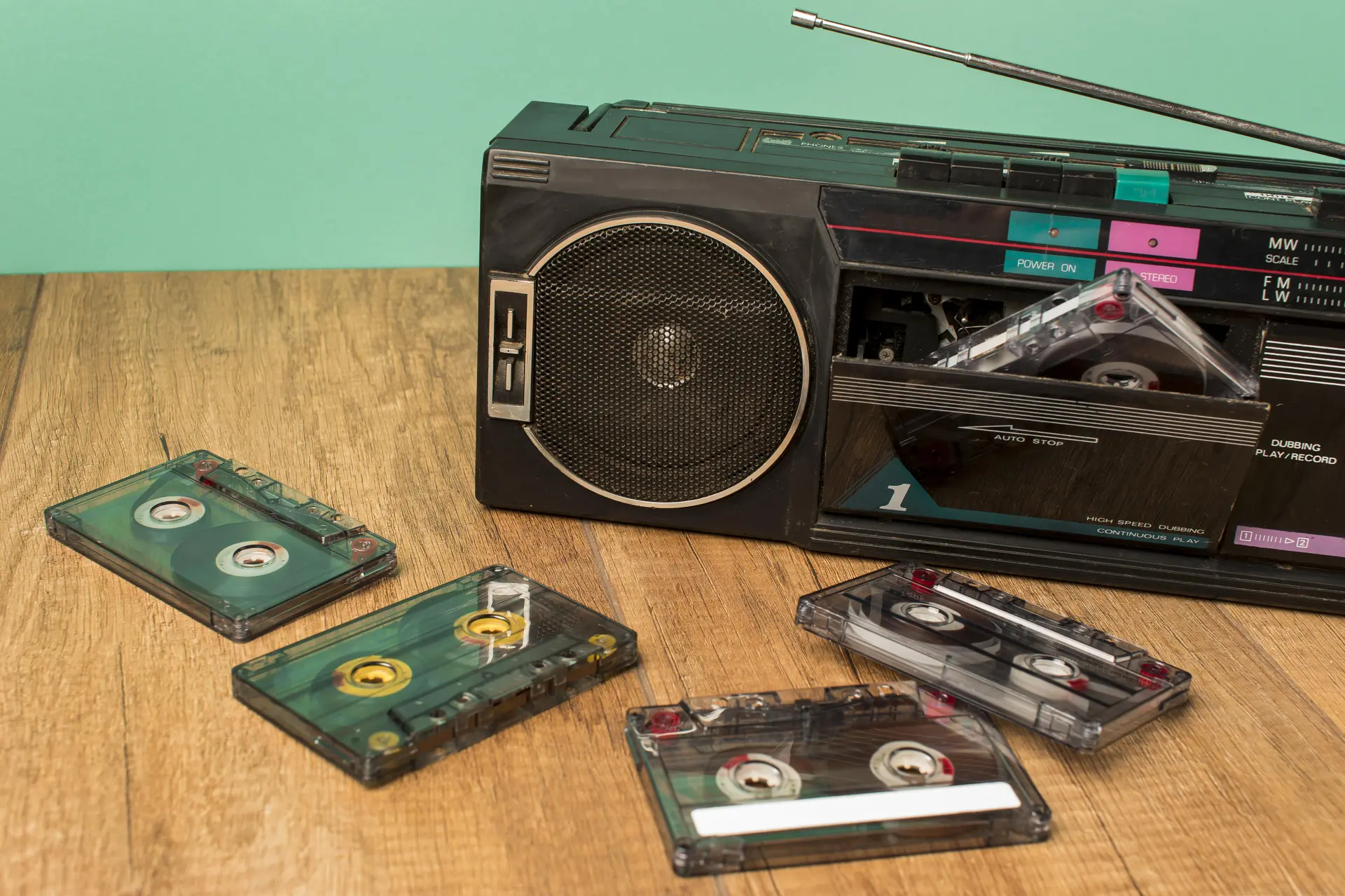 Quatre K7 audios et un transistor posés sur une table en bois