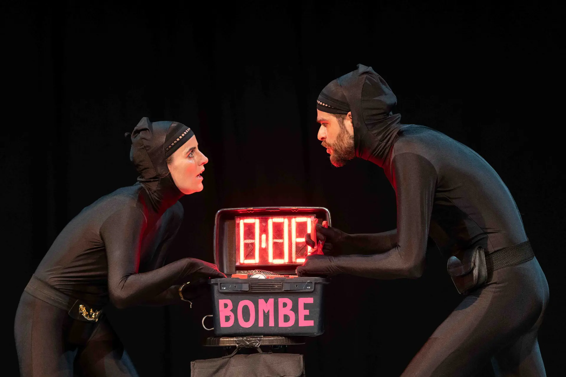 Un couple d'agents secrets habillés en noir essaient de désamorcer une bombe.