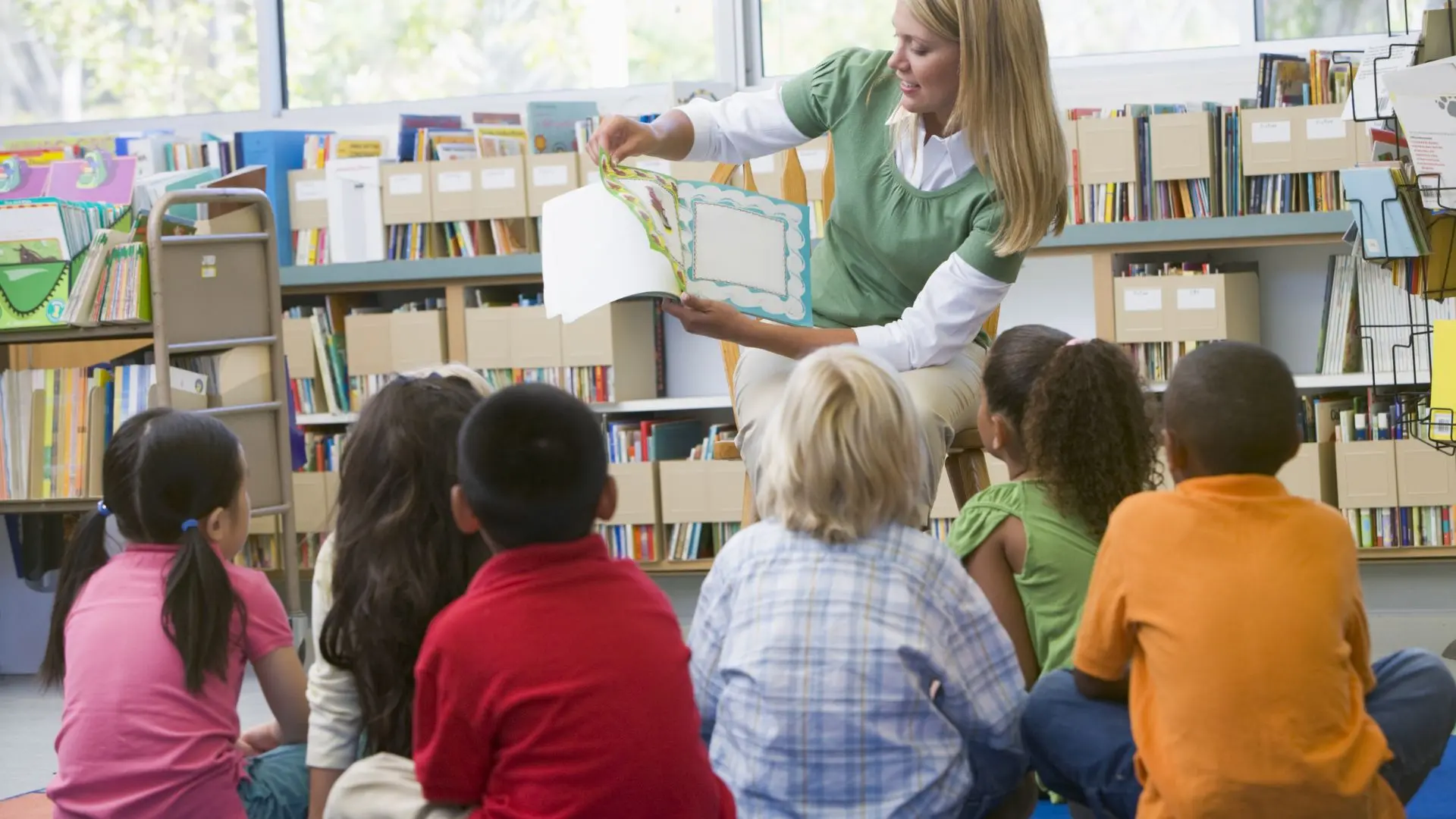 enfants devant une dame qui leur lit un livre