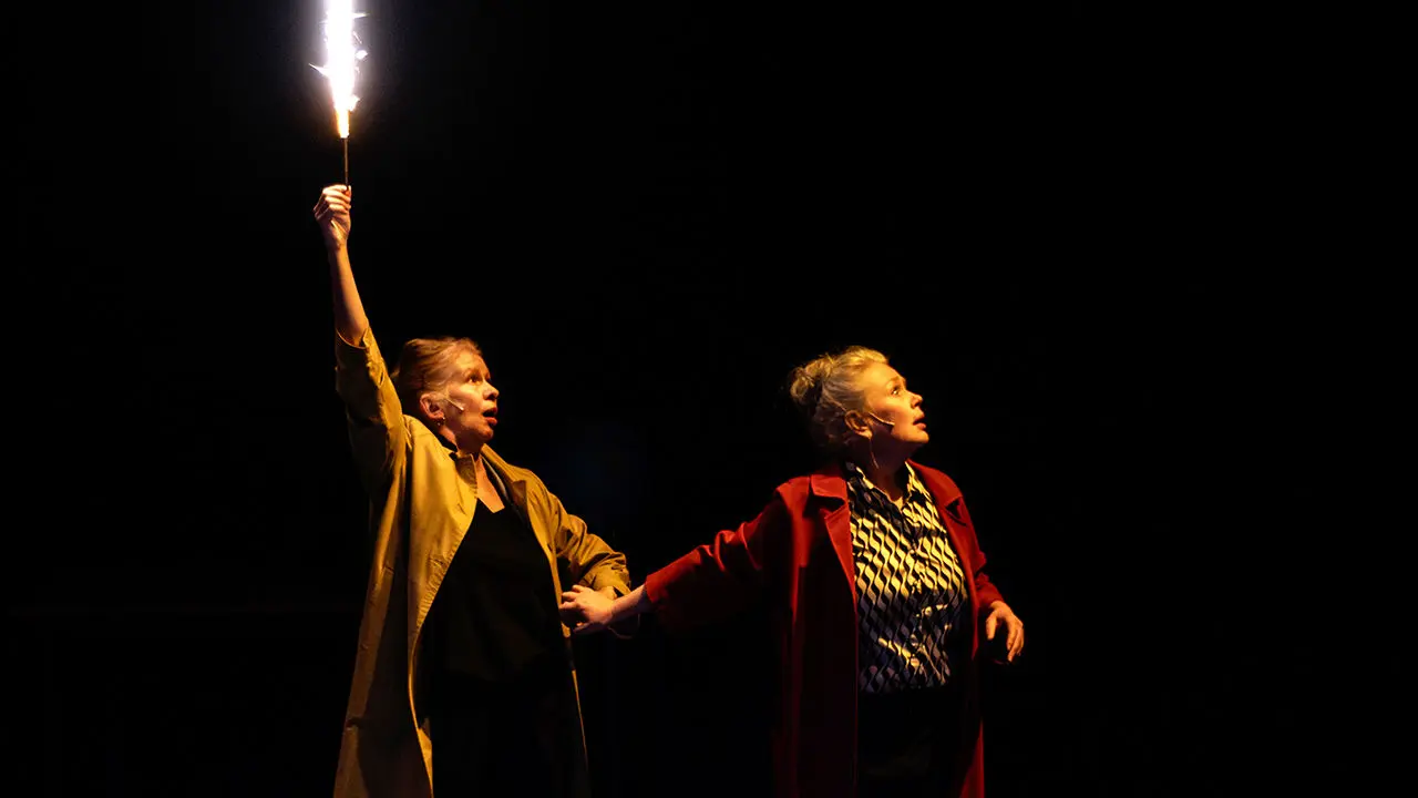 deux artistes avec une flamme à la main sur scène dans le noir