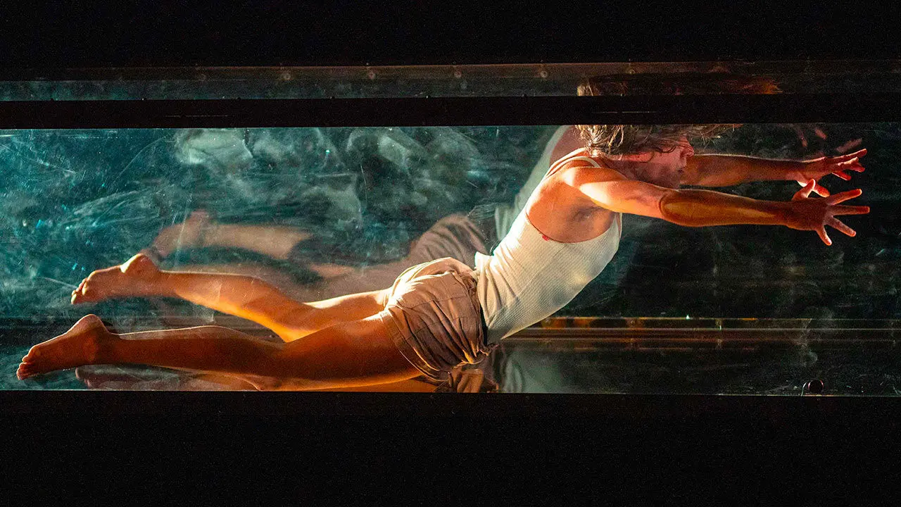 danseur dans une cage vitrée qui tend son corps horizontalement