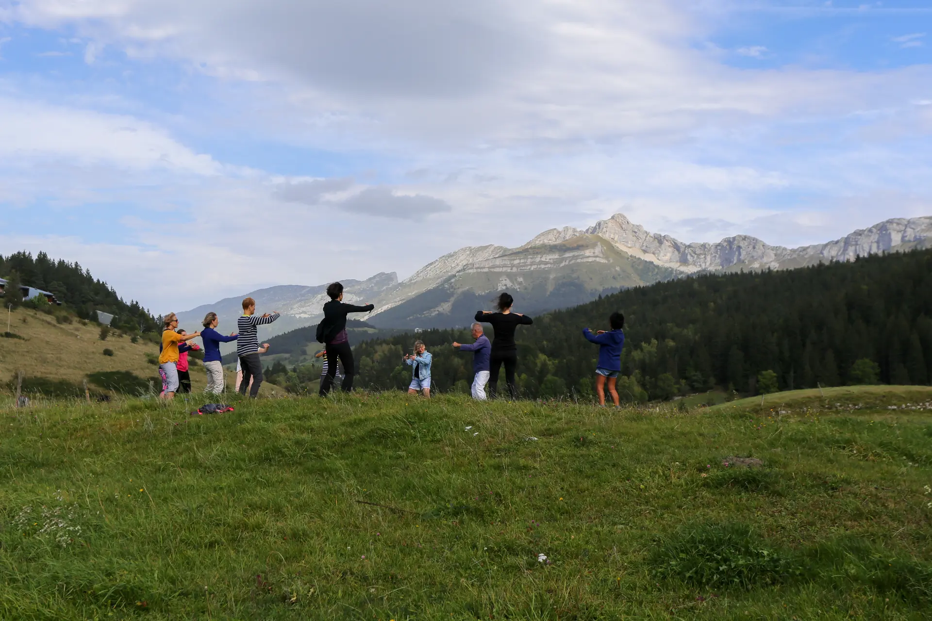 Groupe de personne pratiquant une activité douce en pleine nature, vue sur les montagnes