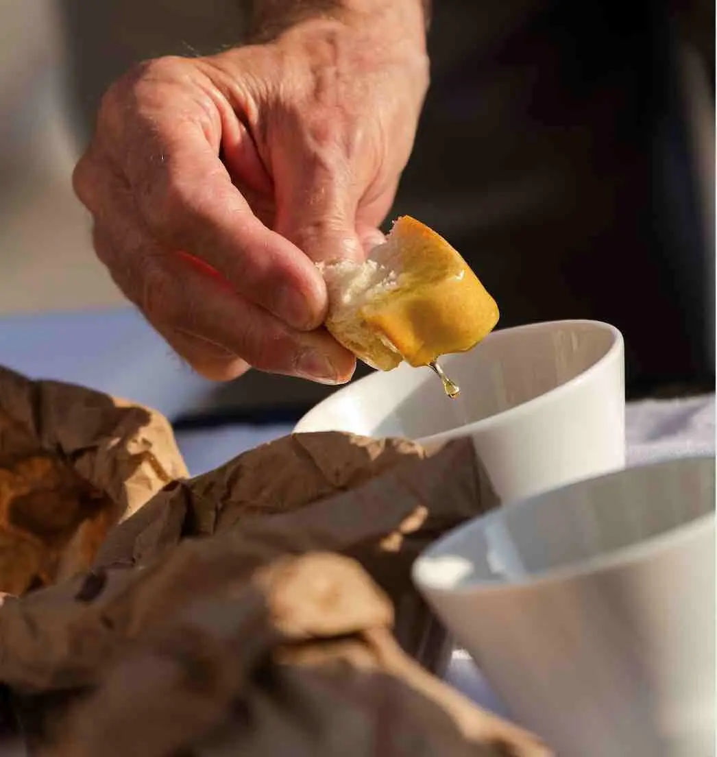 main qui trempe crouton dans huile d'olive
